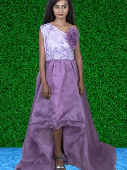 A modern lavender high-low gown with a floral accent on the shoulder. This style is perfect for showing off a great pair of shoes.