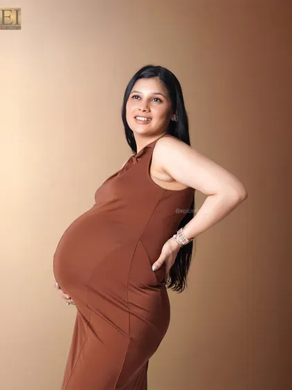 A simple, fitted brown dress that elegantly accentuates the baby bump in this classic studio portrait.