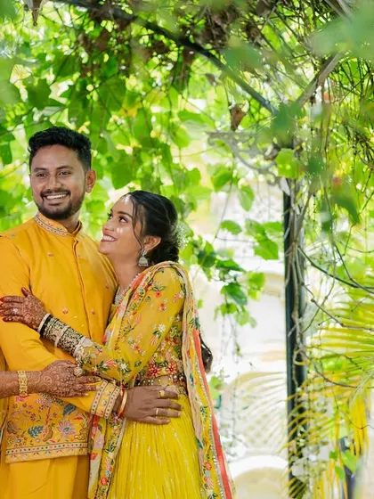 A happy family portrait during the Haldi ceremony, with the couple surrounded by loved ones in a lush, green setting.