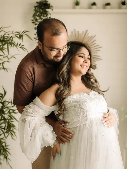 The love and excitement between expectant parents is so beautiful to capture. Here, a couple shares a happy moment in an elegant white gown, surrounded by soft studio light.