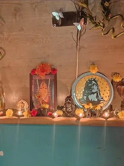 My personal pooja shelf decorated for Karthigai Deepam, featuring my Adiyogi painting, flowers, and many small lamps.