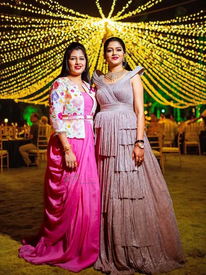 Sister goals. The bride in her rose gold reception gown stands with her sister, who is wearing a custom pink gown with a colorful embroidered jacket that I also designed.