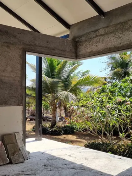 A view from inside the concrete shell of Grove House during construction, looking out into the lush garden.