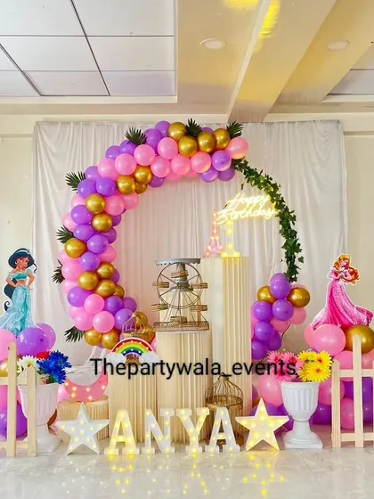 A first birthday princess party with a focus on Jasmine and Aurora, featuring a pink, purple, and gold color scheme.