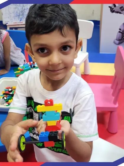 This young builder proudly displays his LEGO creation, a simple robot on wheels. Our programs start with foundational concepts, allowing even our youngest students to build confidence and understand the basics of engineering.
