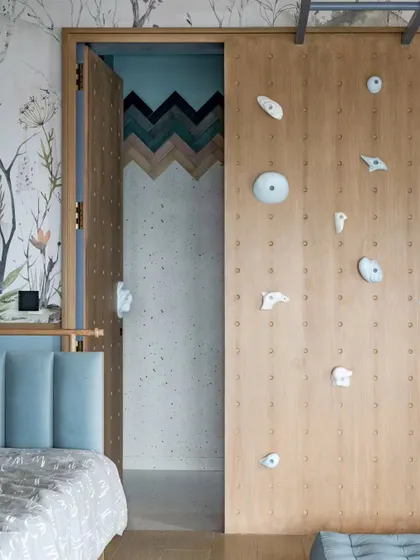 A peek from the bedroom into the ensuite bathroom, where the playful theme continues with colorful chevron tiles. The rock-climbing wall adds an element of adventure.