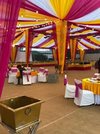 A large wedding tent setup with colorful drapes and organized seating, ready for a big celebration.
