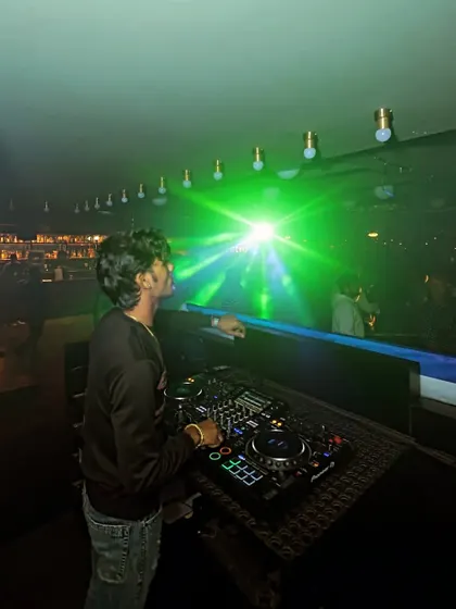 A view from my console, looking out at the dance floor under a web of green laser lights. This is the immersive experience I create.