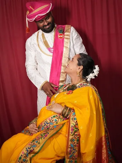A royal-themed maternity shoot with the couple in traditional Maharashtrian attire. The yellow Paithani saree looks stunning.