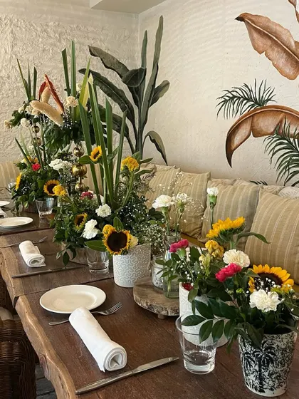 Long table seating at a baby shower, decorated with a series of floral arrangements in varying heights to create visual interest.