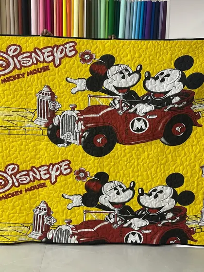 A bright and cheerful Disney-themed quilt featuring Mickey and Minnie Mouse on a drive.