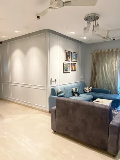 Here, we used classic wall molding to conceal extensive storage, turning a practical necessity into an elegant feature wall. This approach maintains a clean, traditional look in the living room while maximizing every square inch of space.