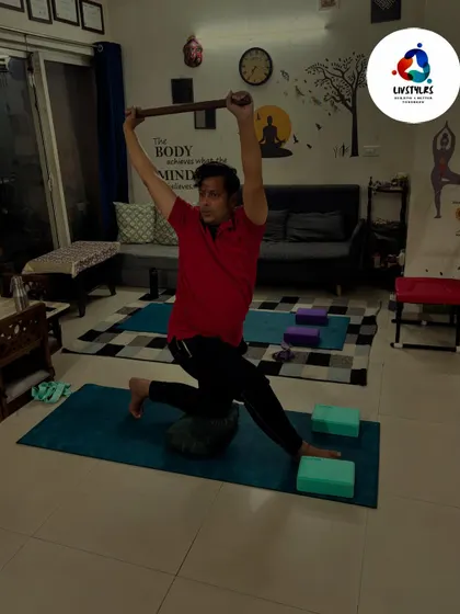 I am demonstrating a seated posture with a stick to improve shoulder mobility and chest opening. This simple prop can be a powerful tool for correcting rounded shoulders.