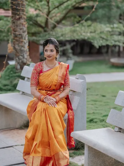 A serene moment captured outdoors. The natural light beautifully highlights the soft, radiant makeup I created to complement her traditional yellow and red Kanjeevaram saree.
