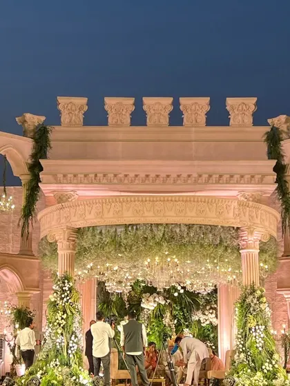 A full view of the Roman mandap being set up, showcasing the grand scale of the architecture and the abundance of floral decor.