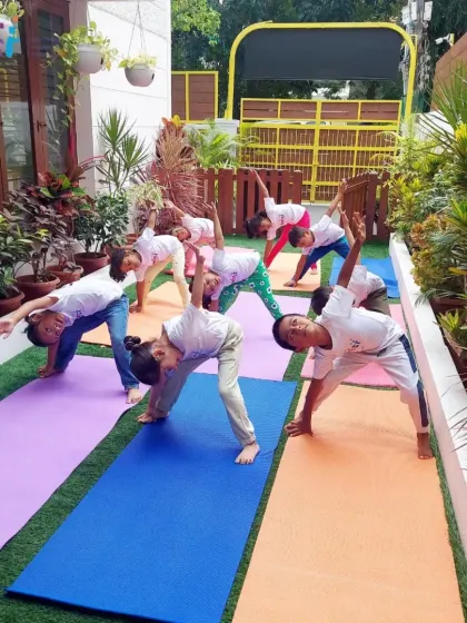 A group of senior children practices the triangle pose together on colorful yoga mats in our garden. Group yoga fosters a sense of unity and shared purpose.
