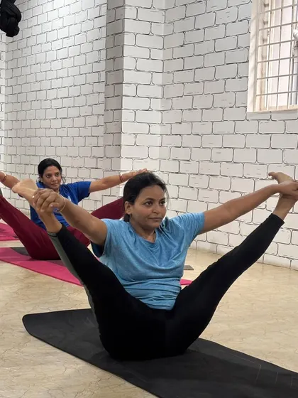 Students in sync, practicing Upavistha Konasana (Wide-Angled Seated Forward Bend), a pose that deeply stretches the hamstrings and inner thighs.