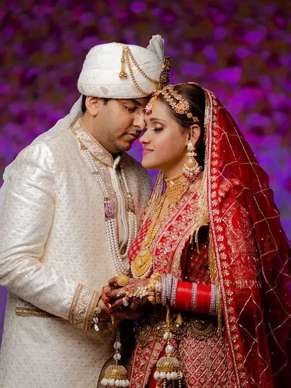 An intimate and romantic portrait against a vibrant purple floral background. The couple's close embrace creates a beautiful, emotional shot.