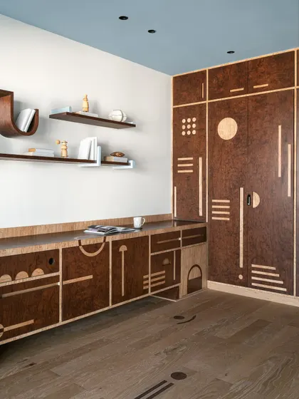 The geometric inlay work on the floor and cabinetry of this multipurpose room creates a cohesive and visually exciting design.