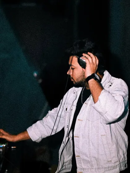 Listening closely to the next track in my headphones, ensuring the mix is seamless.