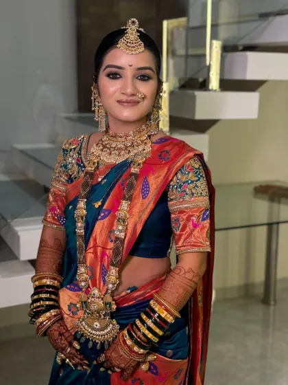 A beautiful portrait of a bride in a blue and orange Paithani saree.