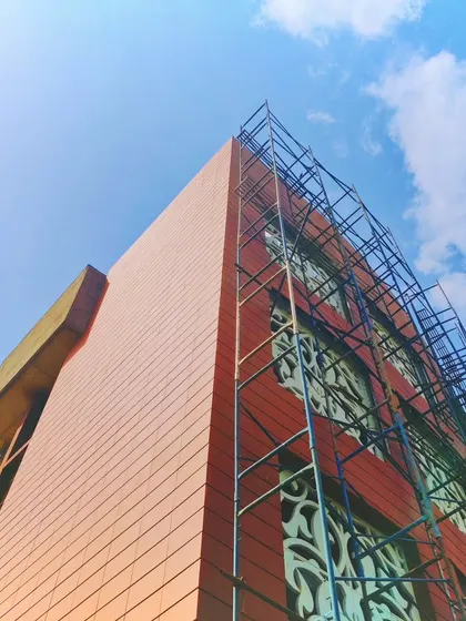Another angle of the Arihant Aspire clubhouse under construction, highlighting the scaffolding against the finished facade panels.