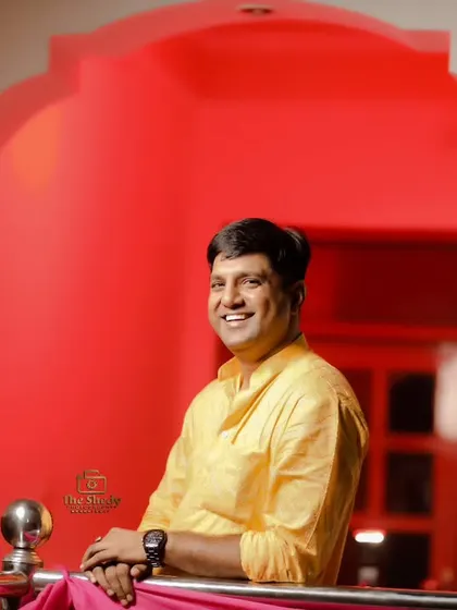 A happy guest enjoying the Haldi festivities. The vibrant red background makes his yellow kurta pop in this portrait.