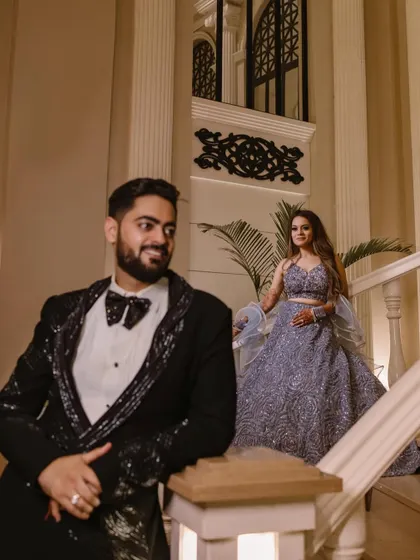 A classic, elegant portrait of the couple on a grand staircase, showcasing the beautiful architecture of the venue and their glamorous attire.