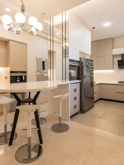 The open kitchen in our Vaswani Exquisite project is a study in minimalist design, with handleless beige cabinets and a seamless flow into the dining area.