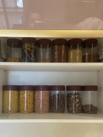 A pantry cabinet filled with pasta, lentils, and whole spices. By taking items out of their bulky packaging, we create more space and a much cleaner look.