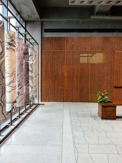 The second-floor waiting lounge, featuring the prayer wheel installation and in-situ terrazzo flooring with brass and aluminum inlays. The design emphasizes Indian craftsmanship within a chic-industrial setting.