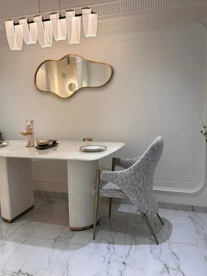 Detail of the dining setup, featuring a fluted table base and a unique, cloud-like mirror. These small, artistic touches are what elevate a design from standard to special.