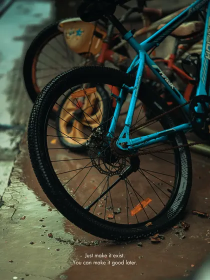 A bicycle wheel on a wet surface. The cool, gritty edit gives this urban detail a moody and cinematic feel.
