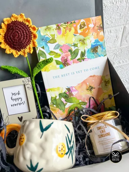 A sunshine-themed birthday hamper featuring a crochet sunflower, a 'smells like sunshine' candle, a floral notebook, and a cute photo frame.