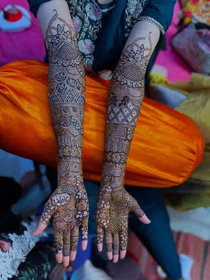 A full view of a bridal henna design, featuring the name "Adil" written on the palm.