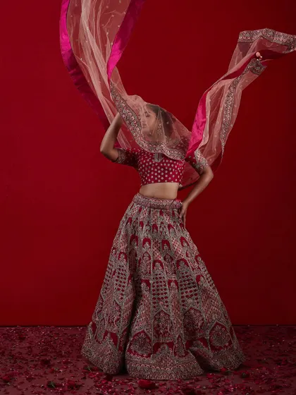 A dynamic shot of a bride with a flowing pink and red dupatta, showcasing a modern and vibrant bridal style.