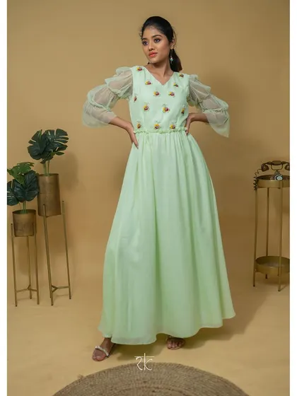 This floor-length georgette dress in a serene teal green is the essence of understated elegance. The design focuses on a graceful silhouette, with delicate threadwork and unique puffed net sleeves for a touch of romance.