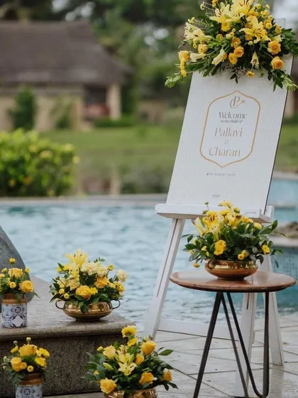 A poolside welcome setup with a custom sign and yellow floral arrangements.