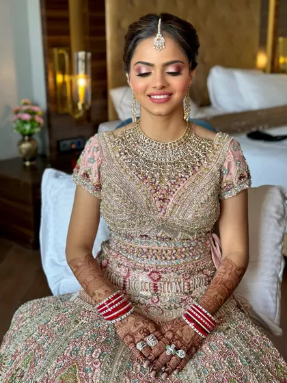 A beautiful smiling shot of the bride. Her eyes are closed, showcasing the soft, blended pink eyeshadow, while her skin glows with a healthy, dewy finish.