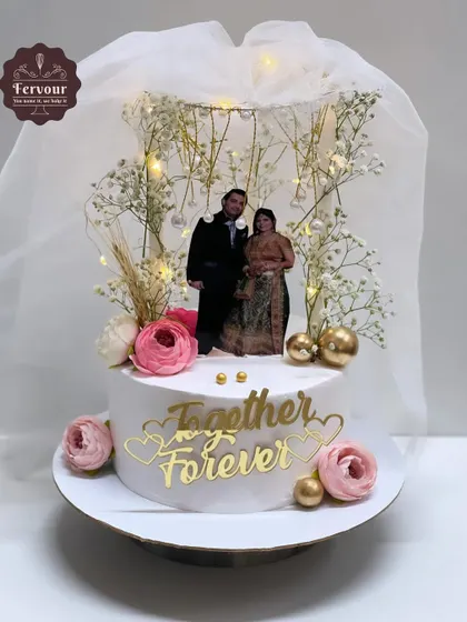 This anniversary cake is designed to be a showpiece, with a "Together Forever" topper and an edible photo of the couple. The design is enhanced with fairy lights and fresh baby's breath for a magical, romantic feel.