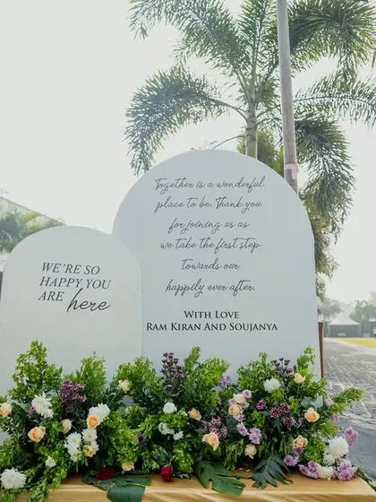 A modern and heartfelt welcome sign, beautifully arranged with flowers, greets guests at the entrance to the venue.