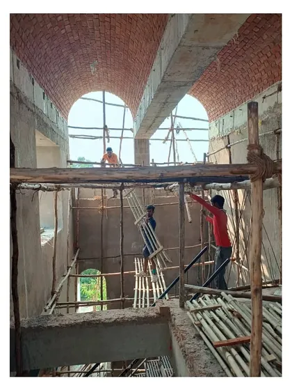 A view from the early construction phase, showing workers on bamboo scaffolding building the massive brick vaults that define the home.