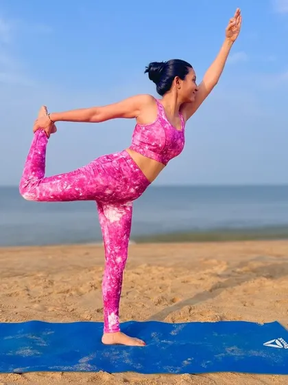 A graceful Natarajasana, or dancer's pose, on the sandy shore. This pose opens the heart and shoulders, and practicing it by the sea feels like a dance with the elements of sun, sand, and water.