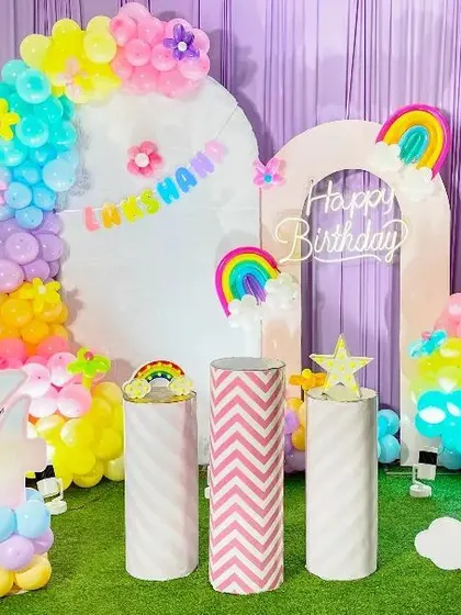 A closer view of the Rainbow theme setup. You can see the details of the "Happy Birthday" sign inside the arch, the custom-wrapped pedestals, and the small balloon arrangement for the number '4'.