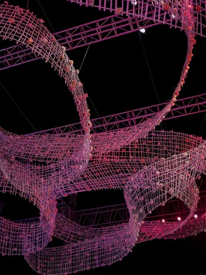 An upward view of the massive, flowing crystal-like ribbons suspended from the lighting rig. This detail highlights the intricate craftsmanship and engineering required for such large-scale hanging installations.