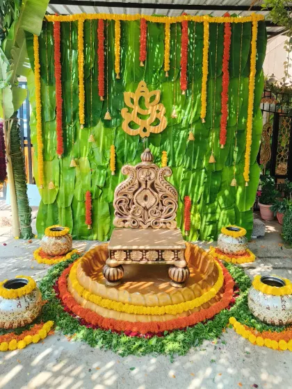 This is a beautiful example of my traditional decor, perfect for a naming ceremony or Seemantham. The backdrop is made of fresh banana leaves, adorned with marigold garlands and a central Ganesha motif, with an ornate seat ready for the ceremony.