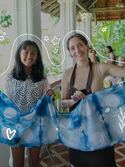 Two guests proudly hold up their finished Shibori piece, showcasing a beautiful pattern of circles created with a simple binding technique. It's a wonderful souvenir from a day of creative exploration in Goa.