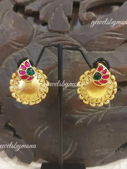 These Dakshinaya studs feature a beautiful combination of pink and green stones on a textured gold base, offering a classic and colorful look suitable for any festive occasion.