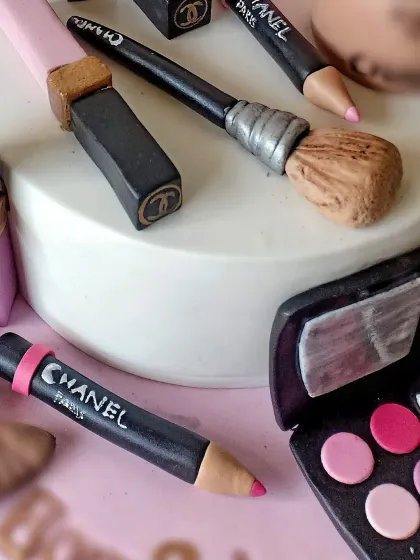 Another angle of the makeup cake, showing the handcrafted lipstick, eyeliner pencil, and brushes.