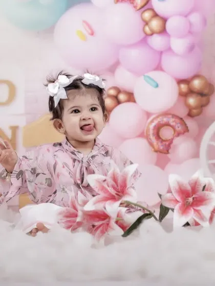 A playful moment captured amidst a cloud of soft fluff and pastel balloons. Her cheeky expression shows the fun and relaxed nature of our themed birthday shoots.